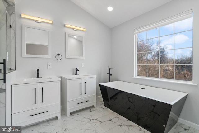 bathroom featuring lofted ceiling, a washtub, and vanity