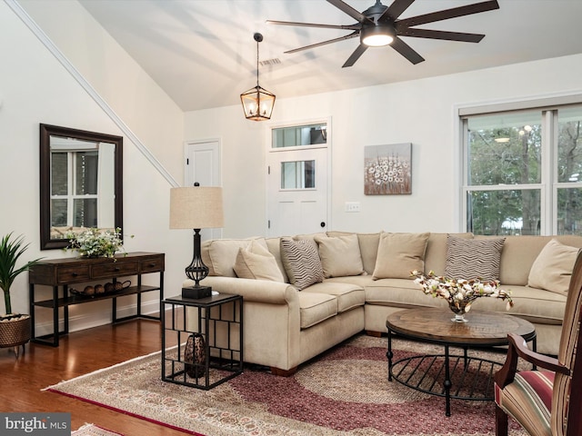 living room featuring ceiling fan with notable chandelier and dark wood-type flooring