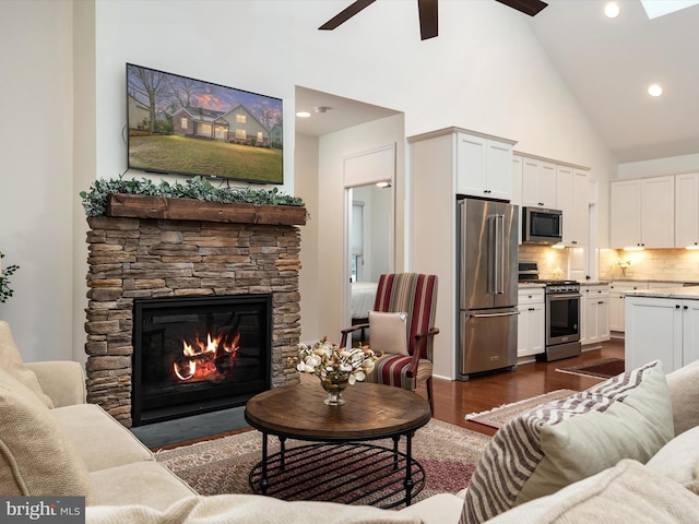 living room with ceiling fan, high vaulted ceiling, dark hardwood / wood-style floors, and a fireplace