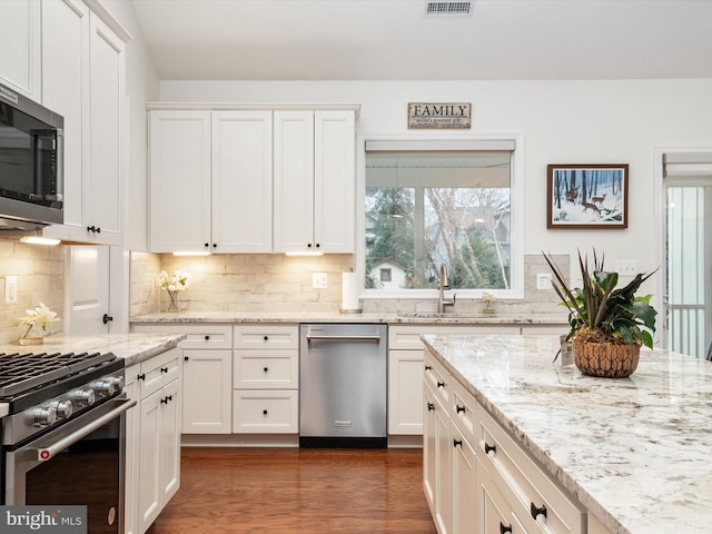 kitchen featuring stainless steel appliances, sink, white cabinets, and light stone counters