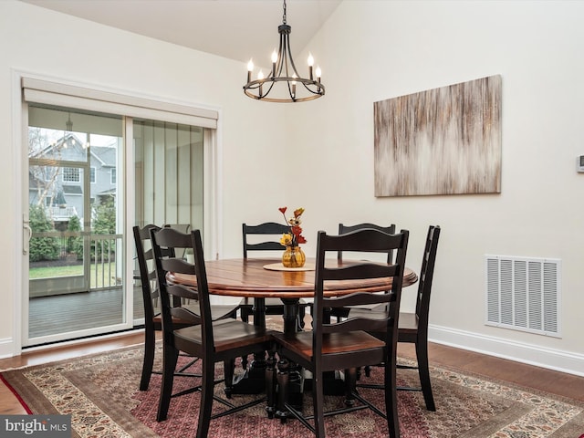 dining space featuring dark hardwood / wood-style flooring, vaulted ceiling, and a chandelier