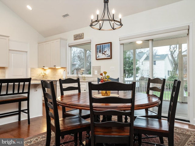 dining room with a notable chandelier, vaulted ceiling, and dark hardwood / wood-style floors