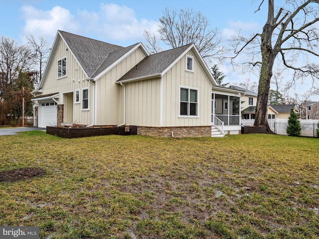 view of side of home featuring a garage, a sunroom, and a lawn