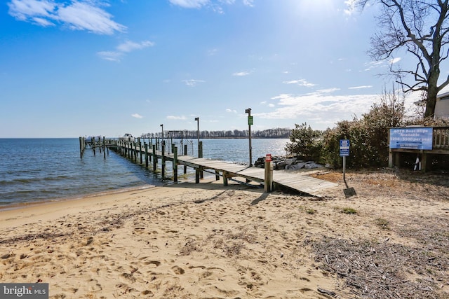 view of dock featuring a water view and a beach view