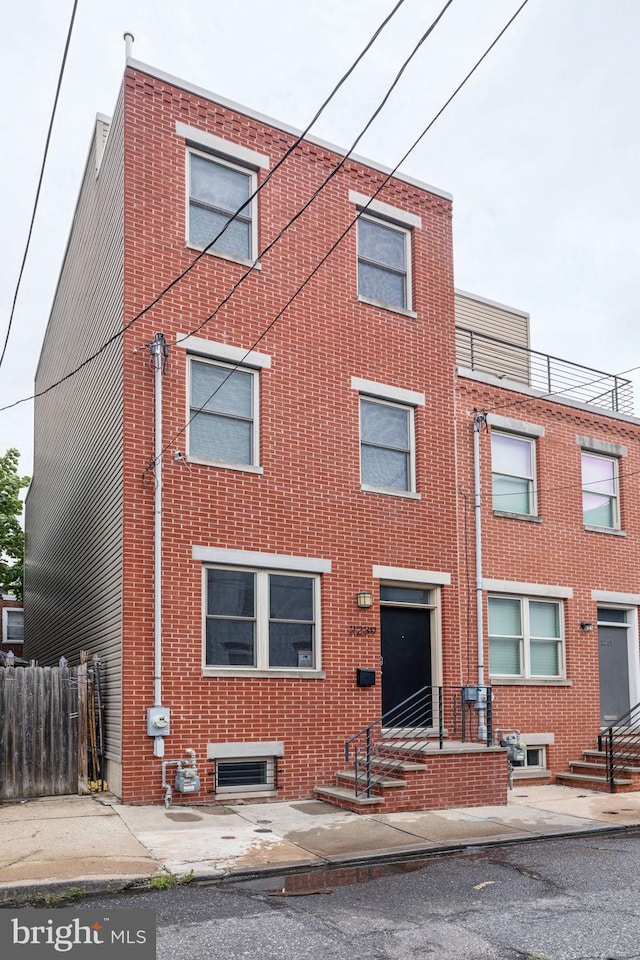 view of front facade with brick siding and fence