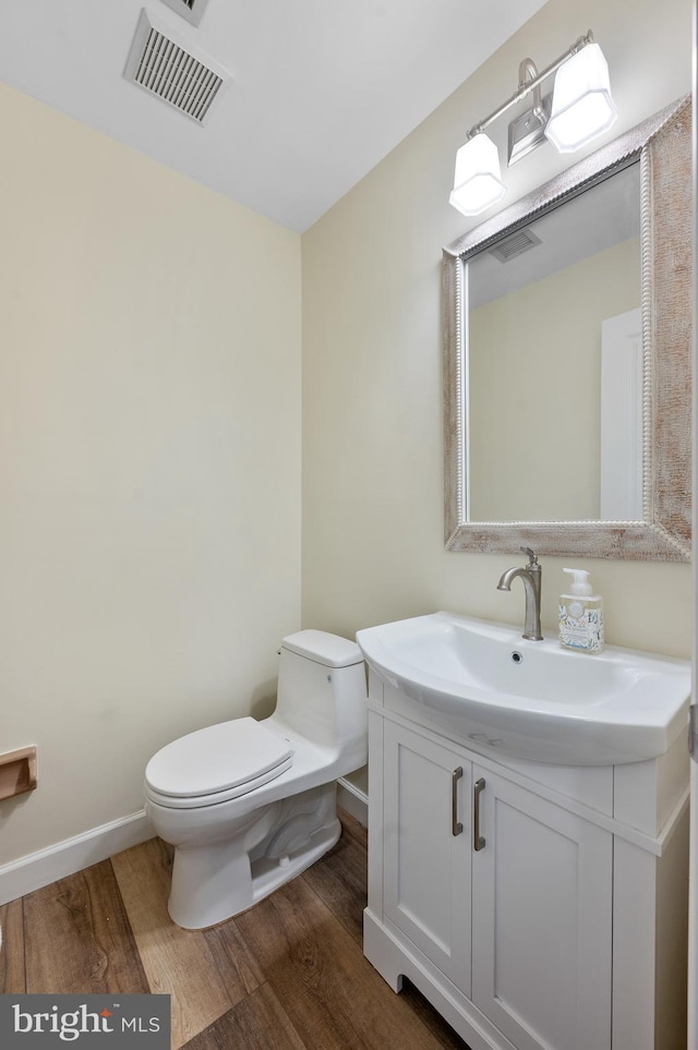 bathroom with hardwood / wood-style flooring, vanity, and toilet