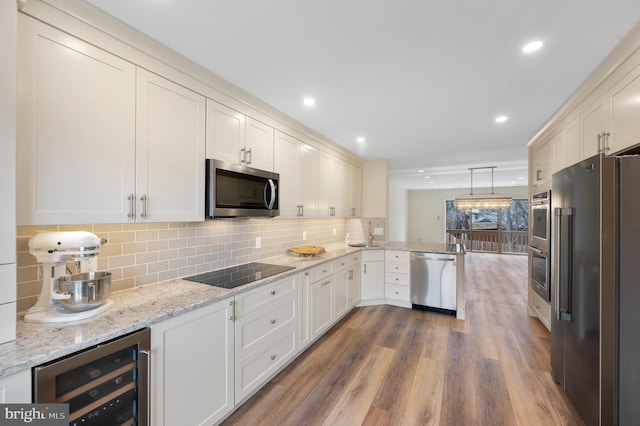 kitchen featuring white cabinetry, decorative light fixtures, stainless steel appliances, and beverage cooler