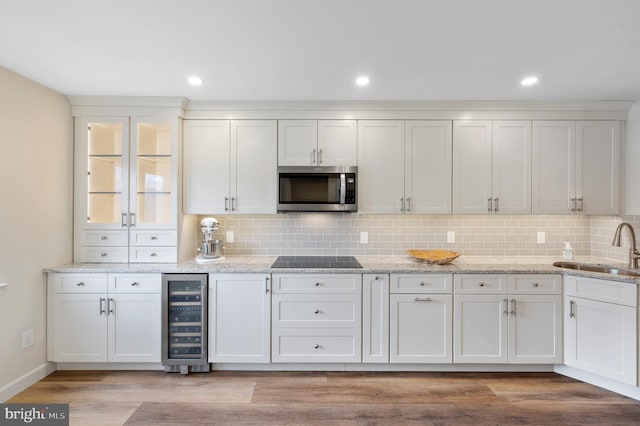 kitchen featuring sink, light hardwood / wood-style flooring, backsplash, wine cooler, and white cabinets