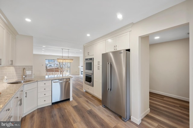 kitchen featuring appliances with stainless steel finishes, sink, pendant lighting, and white cabinets