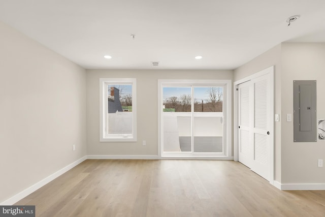 spare room featuring electric panel and light hardwood / wood-style flooring