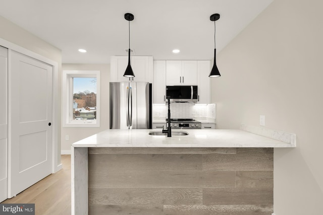 kitchen featuring hanging light fixtures, stainless steel appliances, kitchen peninsula, and white cabinets