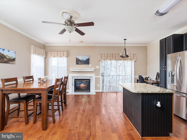 dining space with ceiling fan, ornamental molding, a fireplace, and light hardwood / wood-style floors