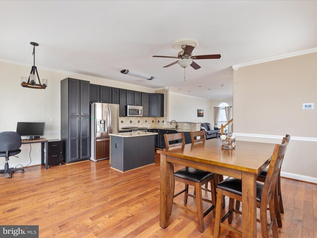 dining area with ornamental molding, sink, ceiling fan, and light wood-type flooring