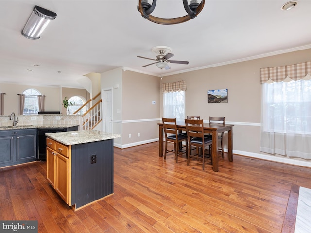 kitchen featuring dark hardwood / wood-style floors, sink, ornamental molding, a center island, and light stone counters