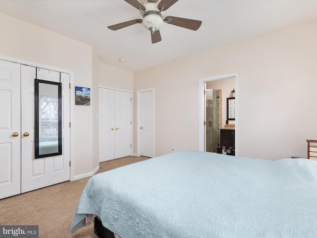 bedroom with ceiling fan, light colored carpet, multiple closets, and ensuite bathroom