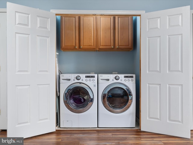 clothes washing area featuring cabinets, washer and dryer, and dark hardwood / wood-style flooring