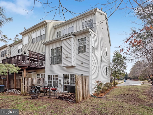 rear view of property with a wooden deck, a yard, and central AC