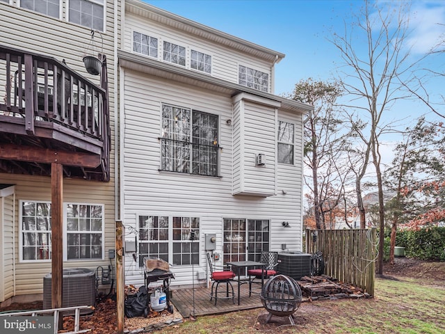 rear view of house with a fire pit, central air condition unit, and a deck