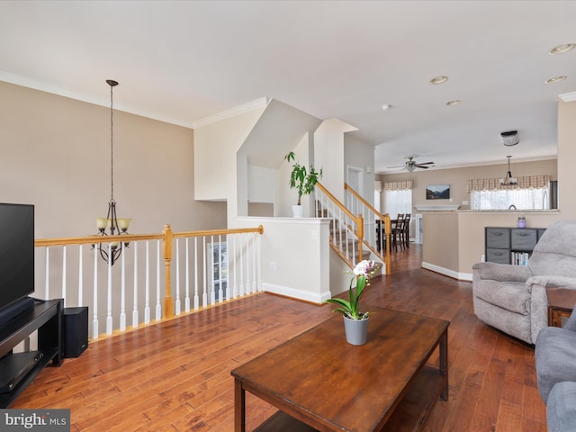 living room featuring hardwood / wood-style floors, ceiling fan with notable chandelier, and ornamental molding