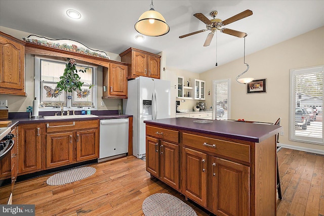 kitchen featuring lofted ceiling, sink, decorative light fixtures, a kitchen island, and white appliances