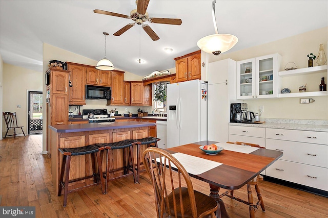 kitchen featuring a center island, a kitchen breakfast bar, white appliances, light hardwood / wood-style floors, and white cabinets