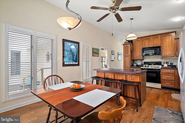 kitchen featuring hardwood / wood-style flooring, a breakfast bar area, pendant lighting, and gas range oven