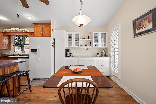 kitchen featuring dishwasher, pendant lighting, white refrigerator with ice dispenser, light hardwood / wood-style floors, and white cabinets