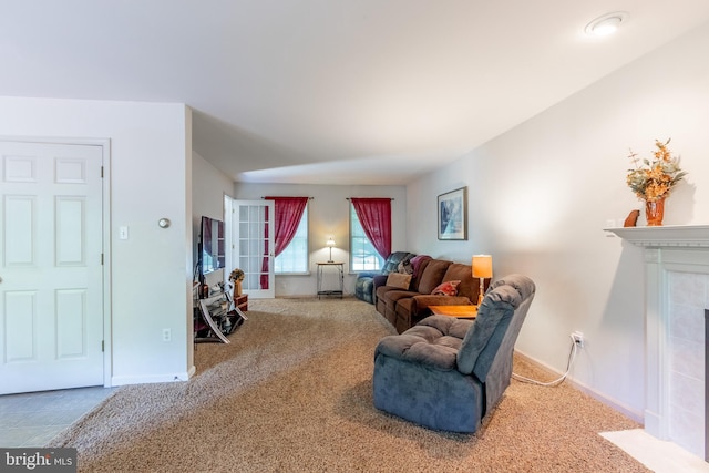 living room with a tiled fireplace and carpet floors