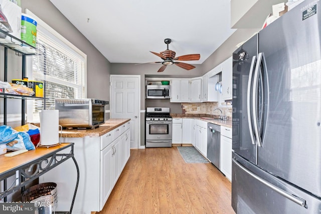 kitchen with sink, ceiling fan, stainless steel appliances, white cabinets, and light wood-type flooring