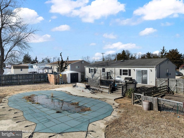 rear view of property with a pool side deck, a storage shed, and a patio