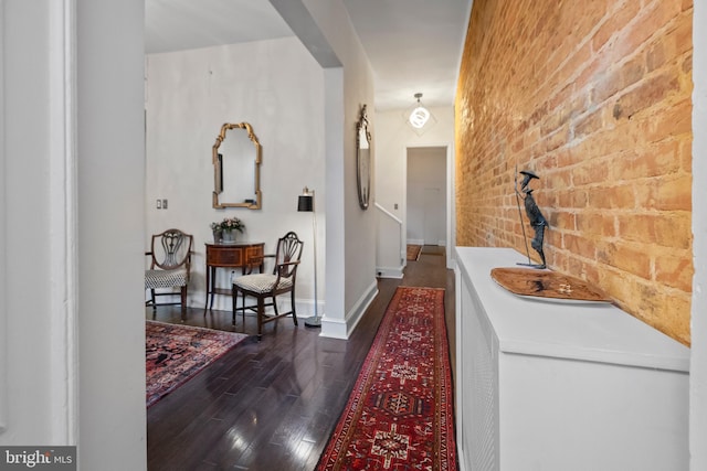 hall featuring brick wall and dark hardwood / wood-style floors