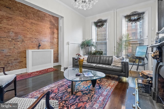 living room with an inviting chandelier, ornamental molding, brick wall, and dark hardwood / wood-style floors