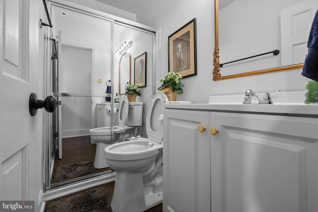 bathroom with a bidet, vanity, wood-type flooring, and toilet