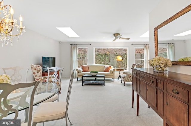 carpeted living room with a skylight and ceiling fan with notable chandelier