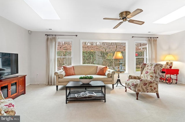 living room with ceiling fan, light colored carpet, and a skylight