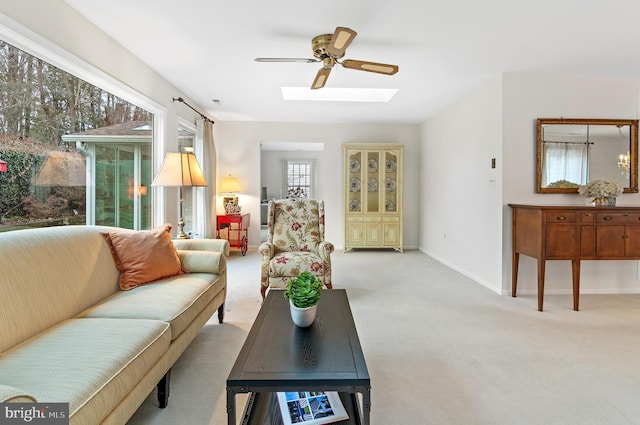 living room featuring light colored carpet, ceiling fan, and a skylight