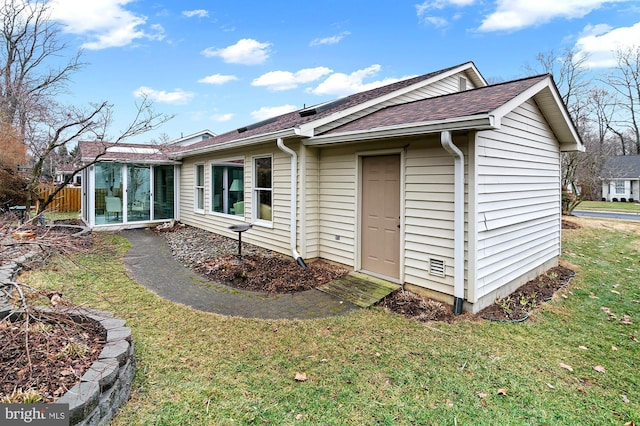 rear view of property featuring a sunroom and a yard