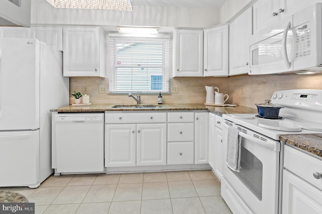 kitchen featuring white cabinetry, sink, white appliances, and dark stone counters