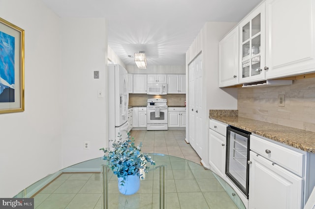 kitchen featuring light tile patterned floors, white appliances, wine cooler, white cabinets, and dark stone counters