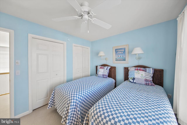 bedroom featuring light carpet, two closets, and ceiling fan