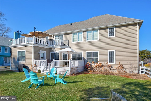 rear view of house with a balcony and a yard