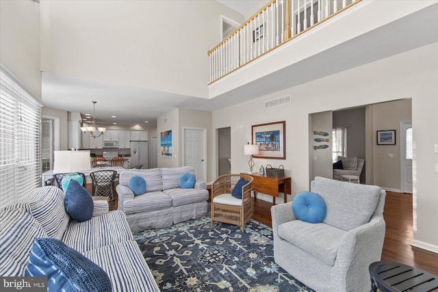 living room featuring hardwood / wood-style flooring, a high ceiling, and a notable chandelier