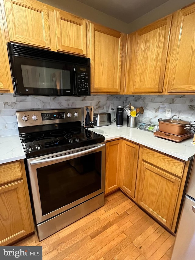 kitchen featuring electric stove, light hardwood / wood-style floors, and backsplash