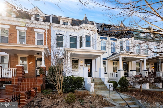 view of property featuring a porch, mansard roof, and brick siding