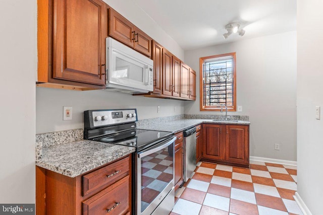 kitchen featuring stainless steel appliances, sink, and light stone counters