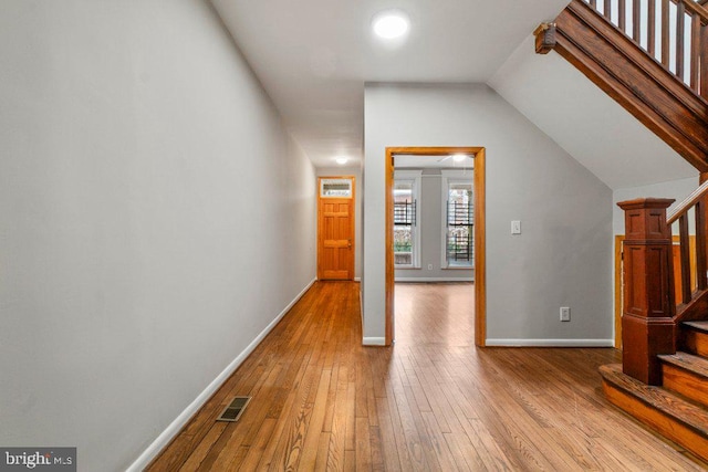 hall featuring vaulted ceiling and light hardwood / wood-style flooring