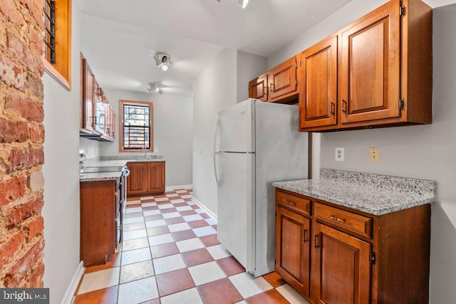 kitchen with electric range, light stone countertops, and white refrigerator