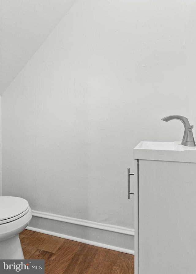 bathroom featuring toilet, lofted ceiling, sink, and hardwood / wood-style floors