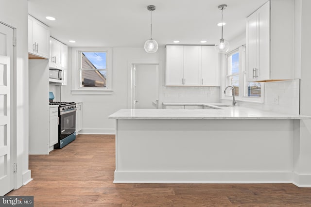 kitchen with kitchen peninsula, white cabinets, and appliances with stainless steel finishes