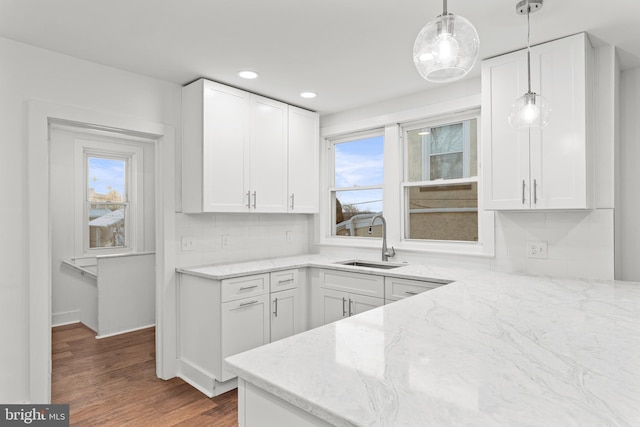 kitchen featuring hanging light fixtures, white cabinetry, light stone countertops, and sink